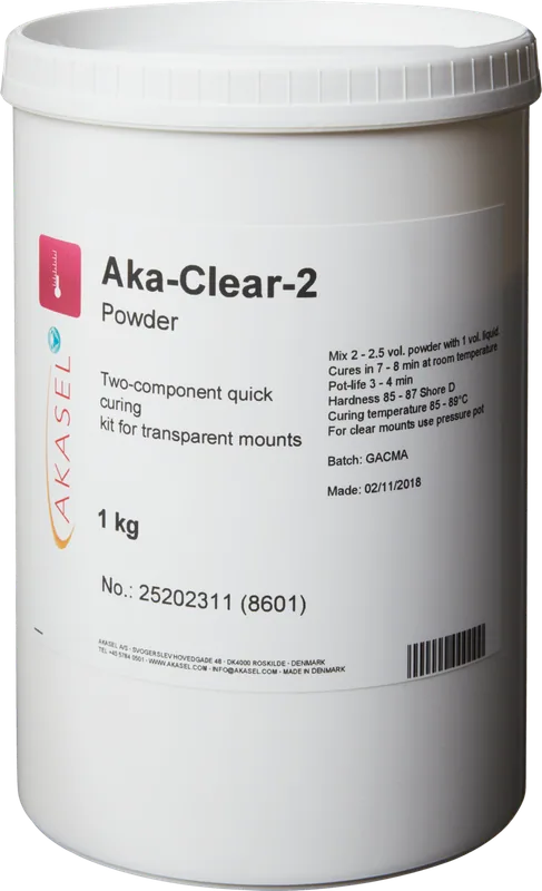 Akasel Aka-Clear-2 Powder: Vit plastbehållare med svart tryck. Etiketten visar Akasel-logotypen och produktbeskrivningen "Aka-Clear-2 Powder." Textinformation inkluderar: "Two-component quick curing kit for transparent mounts," "1 kg," samt detaljerade blandningsinstruktioner (t.ex. "Mix 2 – 2.5 vol. powder with 1 vol. liquid"), härdningstider ("Cures in 7 – 8 min at room temperature") och specifika hårdhetsdetaljer ("Hardness 85 – 87 Shore D"). Ytterligare information omfattar batchnummer, tillverkningsdatum samt säkerhets- och användningsinstruktioner. Speciellt utvecklad för metallografiska applikationer, idealisk för att skapa transparenta inbäddningar för noggrann analys och provberedning.